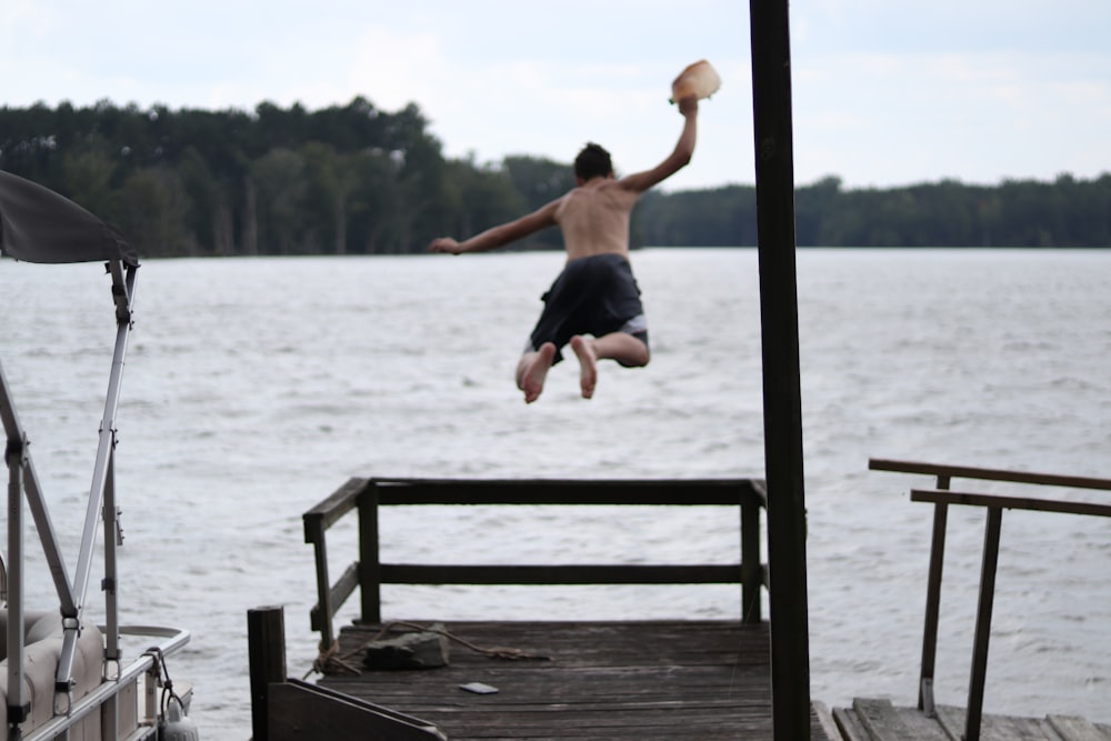 Un hombre saltando de un muelle al agua