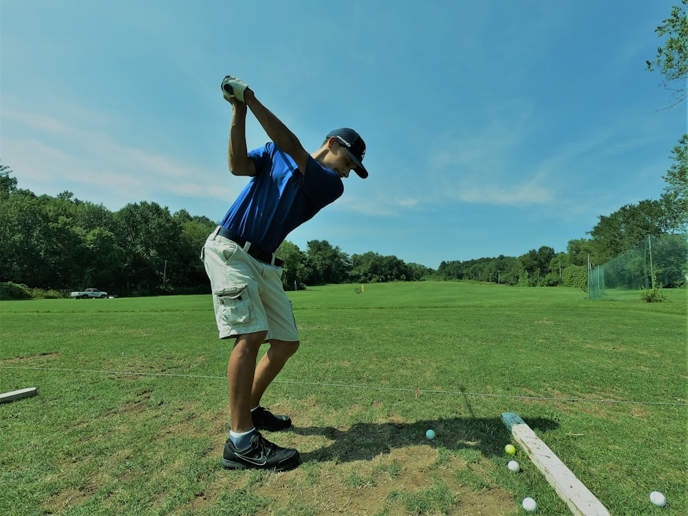 homem na camisa polo azul jogando golfe