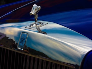 A close-up of a shiny car hood reflecting the Himalayan mountains