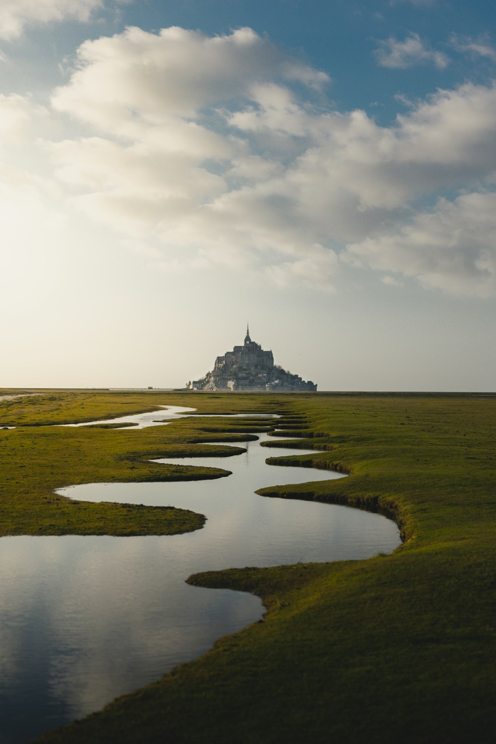 Foto von Grasfeld und spiralförmigem See und grauer Schlosslandschaft