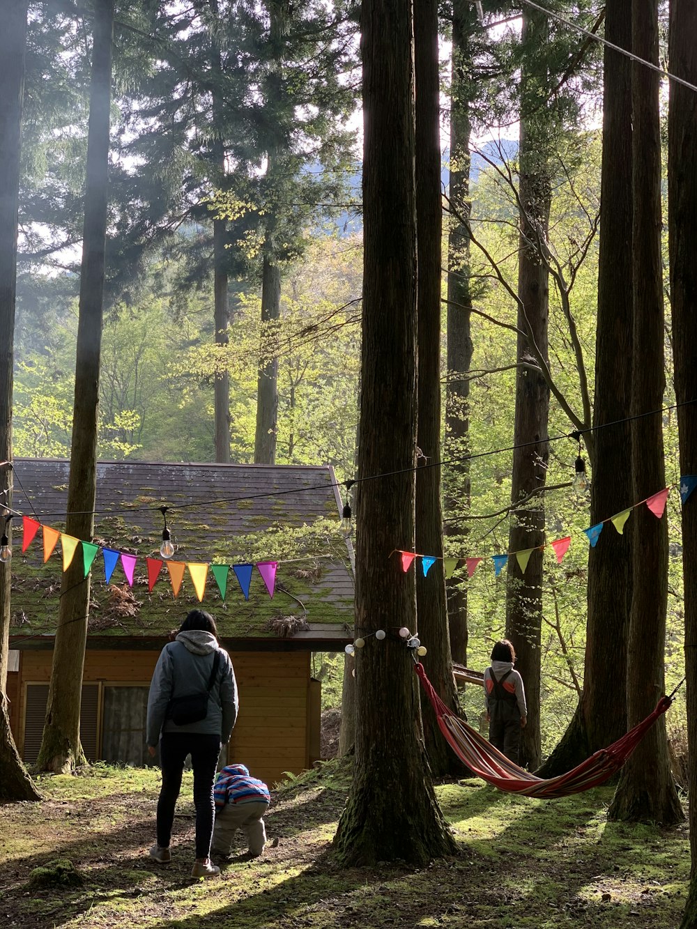 people near brown house surrounded by trees