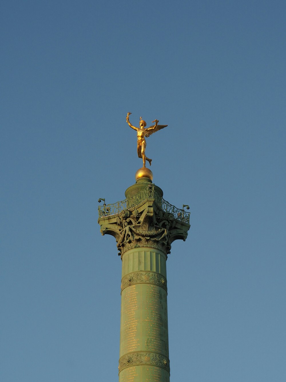 a golden statue on top of a green pillar
