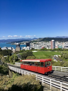 red train on rail with cityscape view underlue sky
