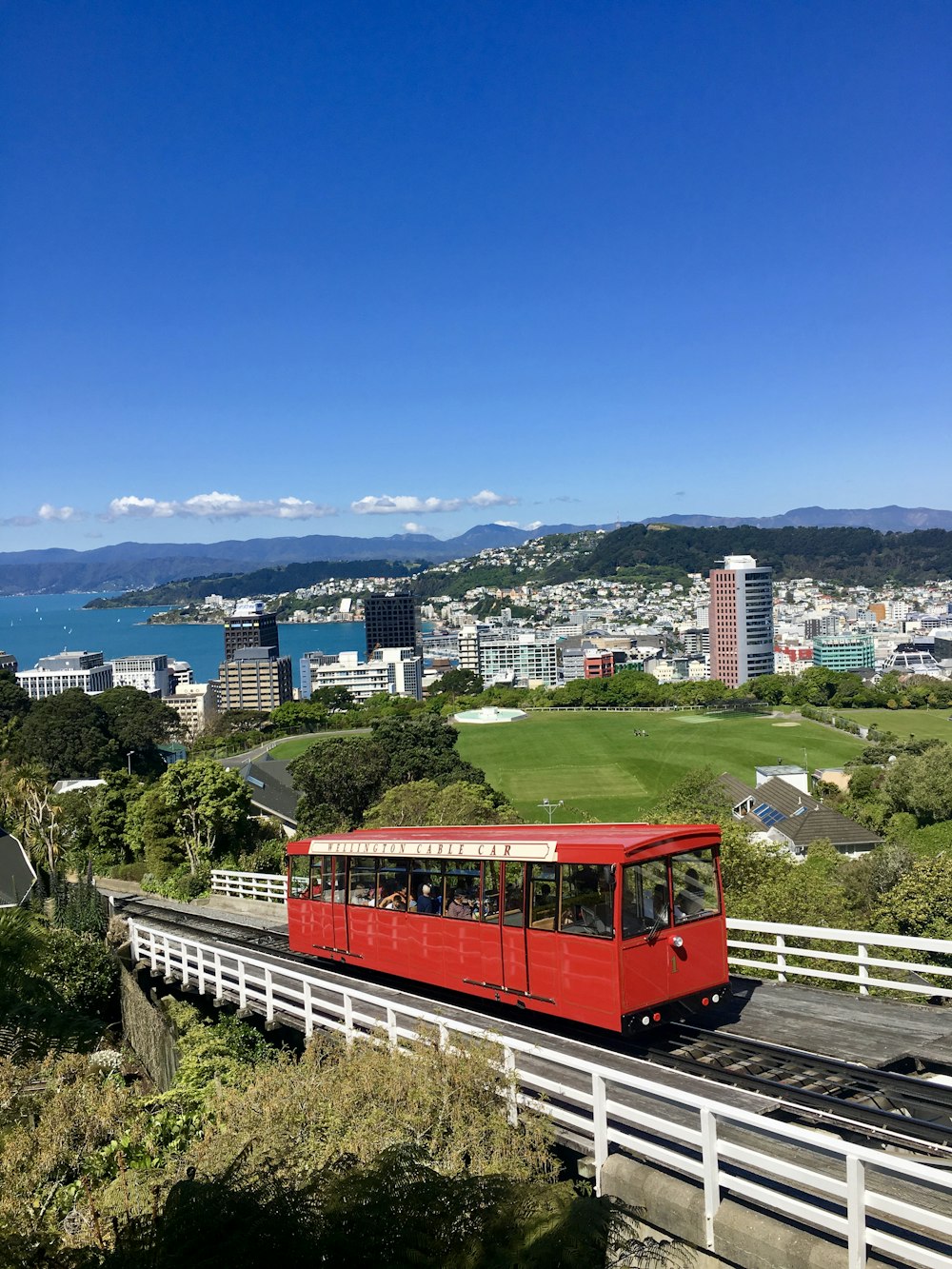 red train on rail with cityscape view underlue sky