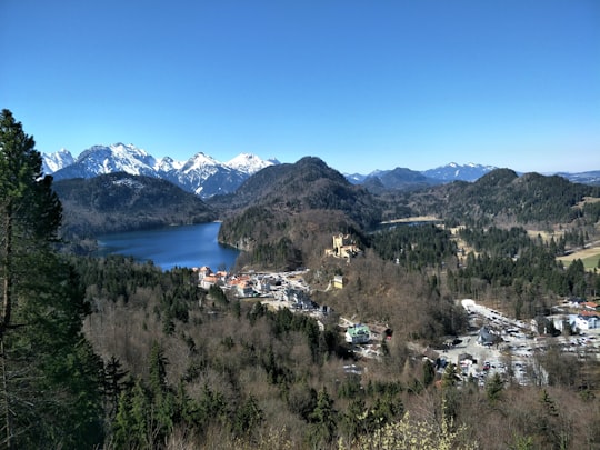 houses near near lake and mountain under blue and white skies in Hohenschwangau Castle Germany