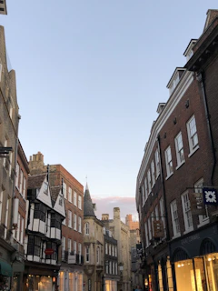 A charming street in West Yorkshire lined with historic buildings and colorful shops under a bright blue sky.