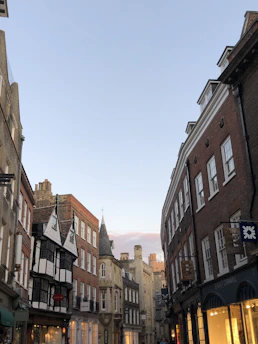 A charming street in West Yorkshire lined with historic buildings and colorful shops under a bright blue sky.