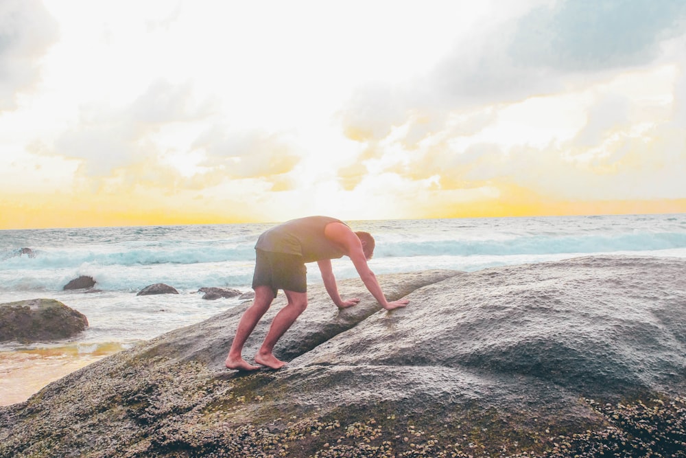 man on gray rock near body of water