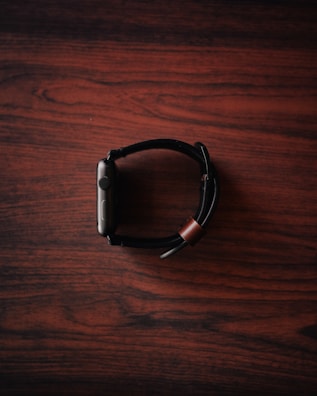 Close-up of a sleek smart watch glowing softly on a wooden table.