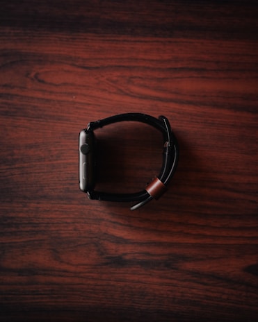 A close-up of a modern smartwatch on a wooden table.