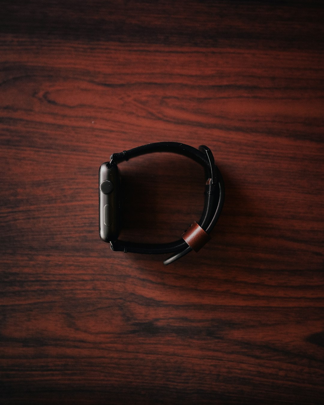 silver Apple Watch on maroon wooden surface