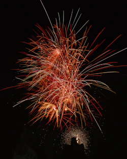Bright fireworks bursting in vibrant colors over a romantic outdoor wedding setting.