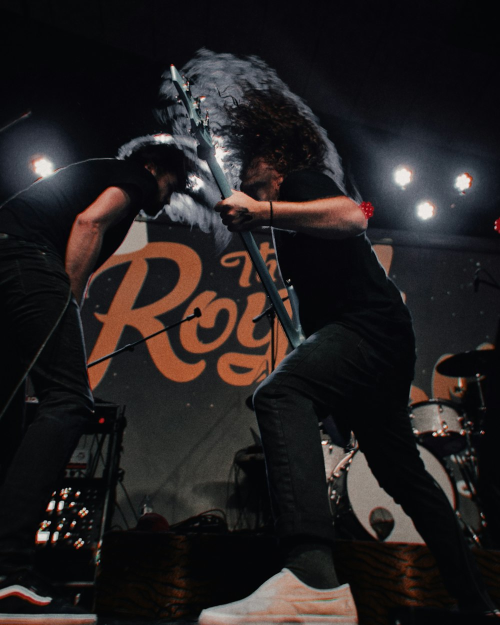 man performing on stage using black electric guitar