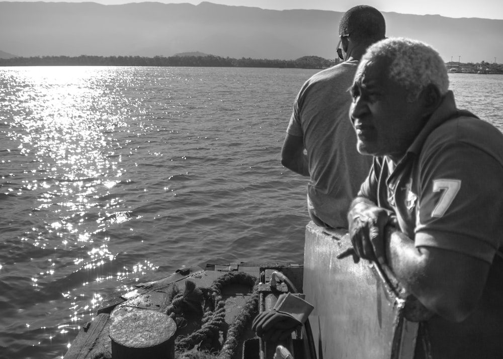 grayscale photo of man looking at ocean