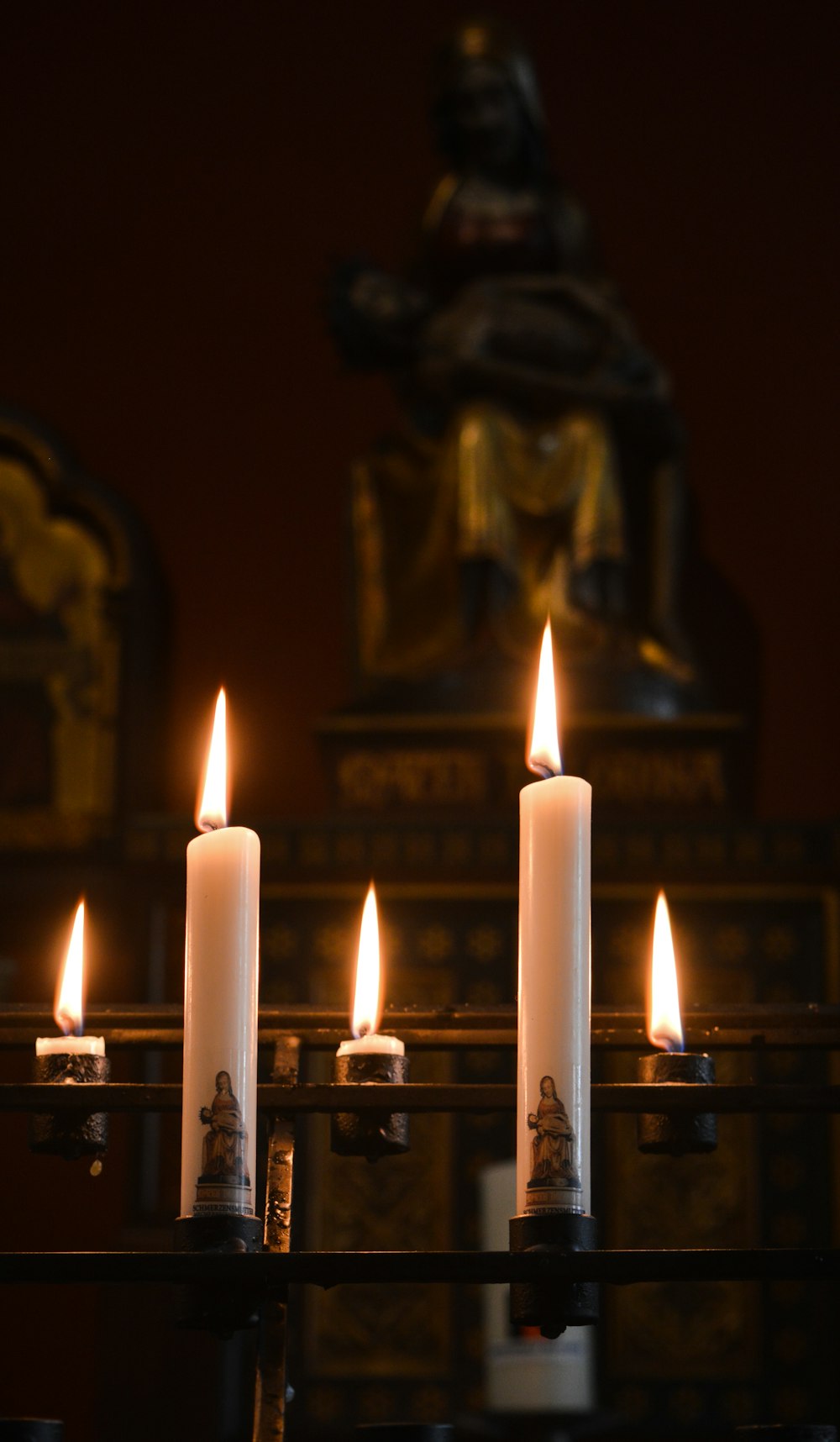 white pillar candles on black metal candle holders close-up photography