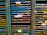 Several storage racks with a variety of colored slats, which appear to be used for organizing or holding paintings or paper. Labels are attached to some of the slats, suggesting organization or categorization. The racks are metallic with peeling paint, indicating frequent use or age.