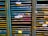 Several storage racks with a variety of colored slats, which appear to be used for organizing or holding paintings or paper. Labels are attached to some of the slats, suggesting organization or categorization. The racks are metallic with peeling paint, indicating frequent use or age.