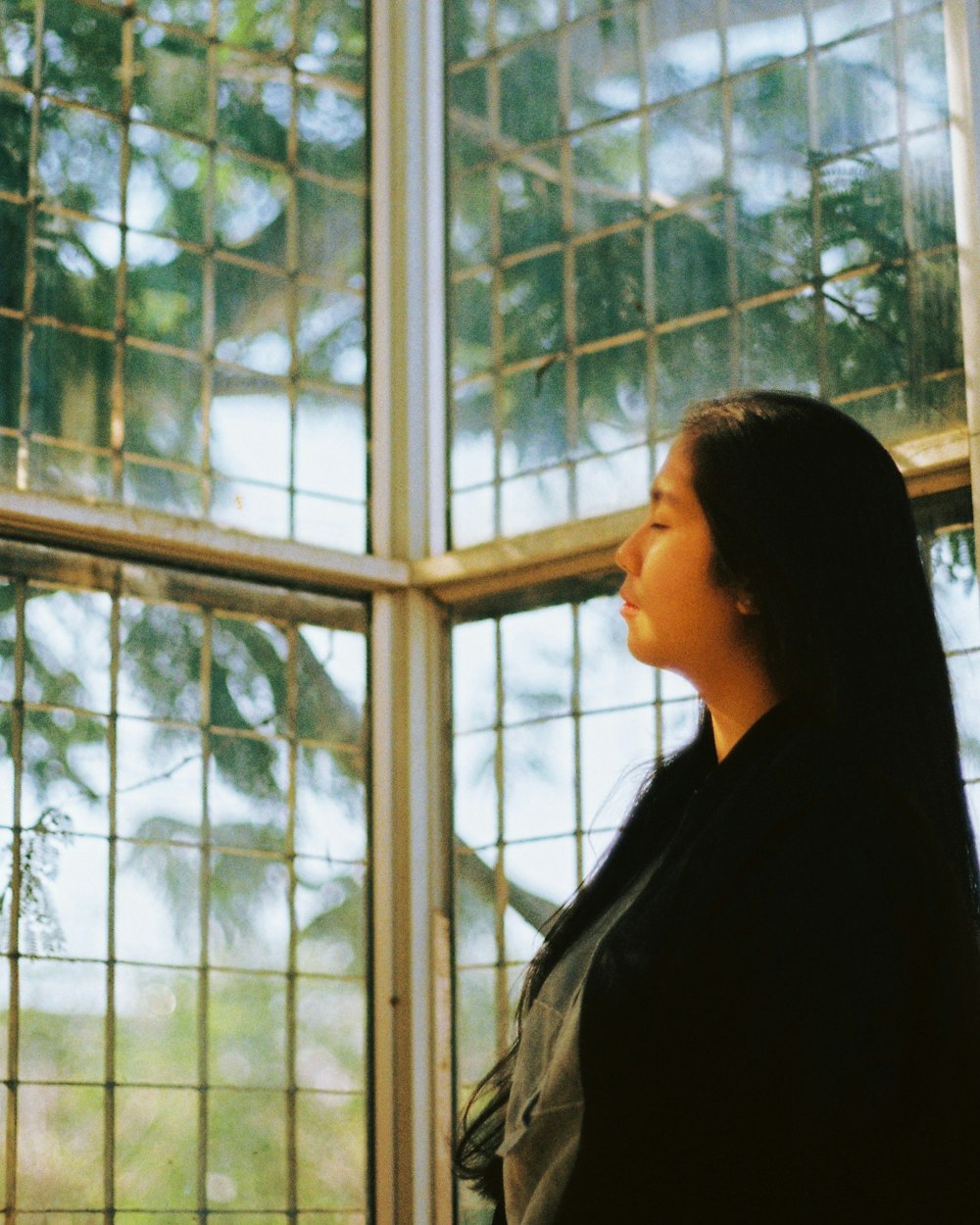 woman in in black top standing in front of glass window