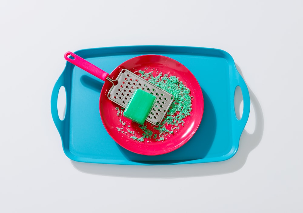 green soap on grey metal grater in round red ceramic plate