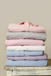folded assorted-color collared button-up shirts on white wooden table