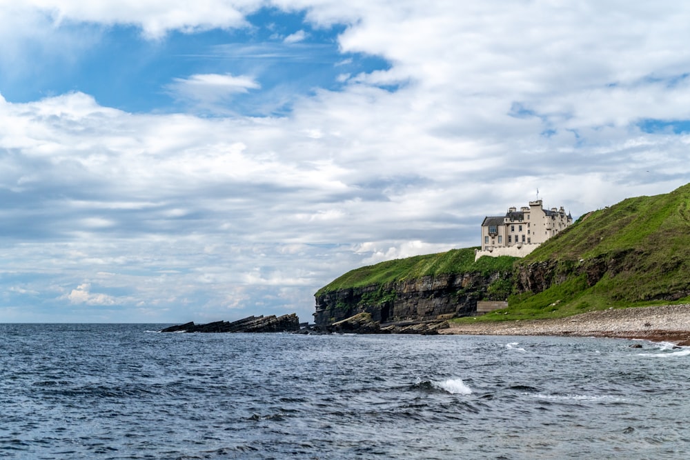 white house near ocean under cloudy sky