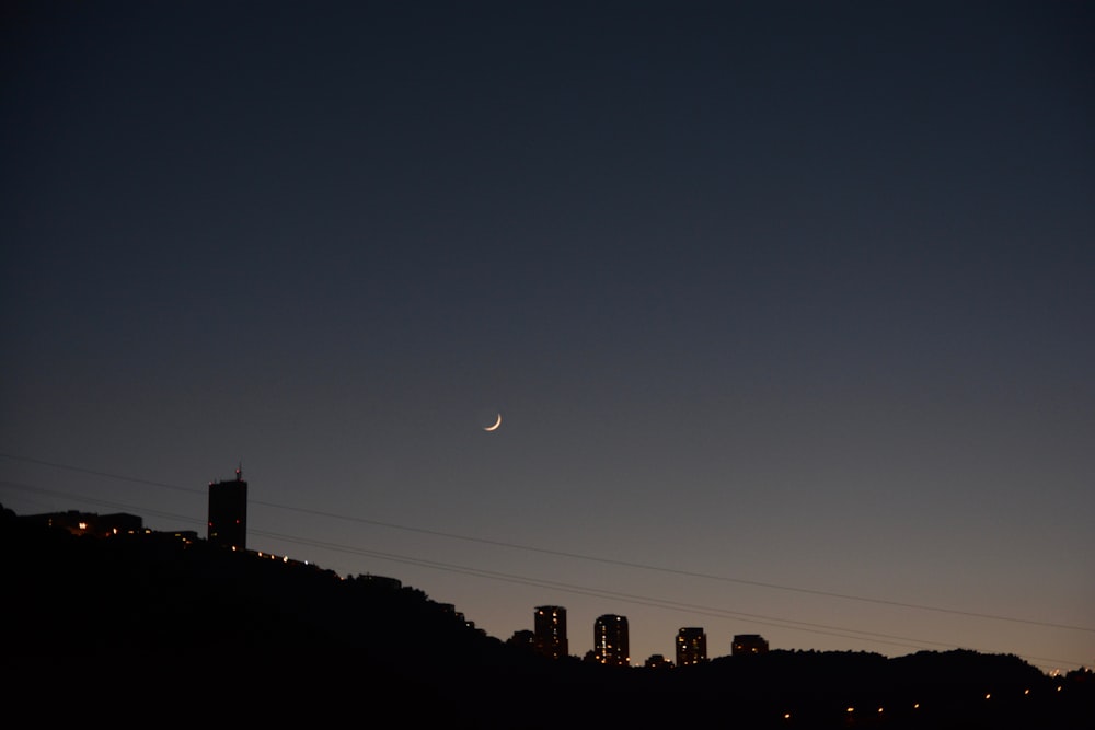 the moon is setting over the city skyline