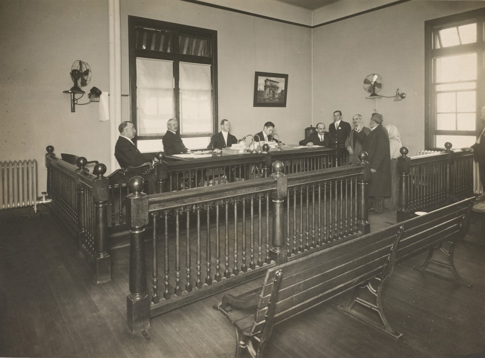 a group of men standing around a wooden desk