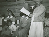 An elder sharing traditional stories with attentive young learners in a sunlit room.