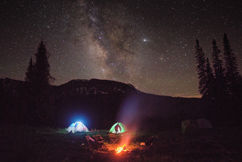 two camping tent with lights under galaxy skies