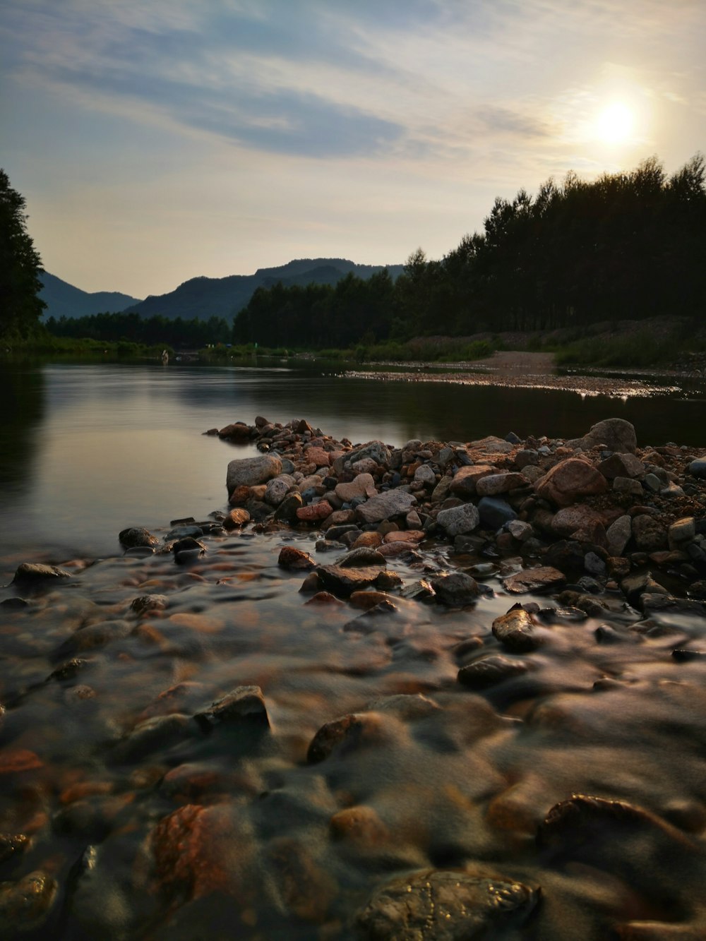 rock formations near body of water surrounded with tall and green trees