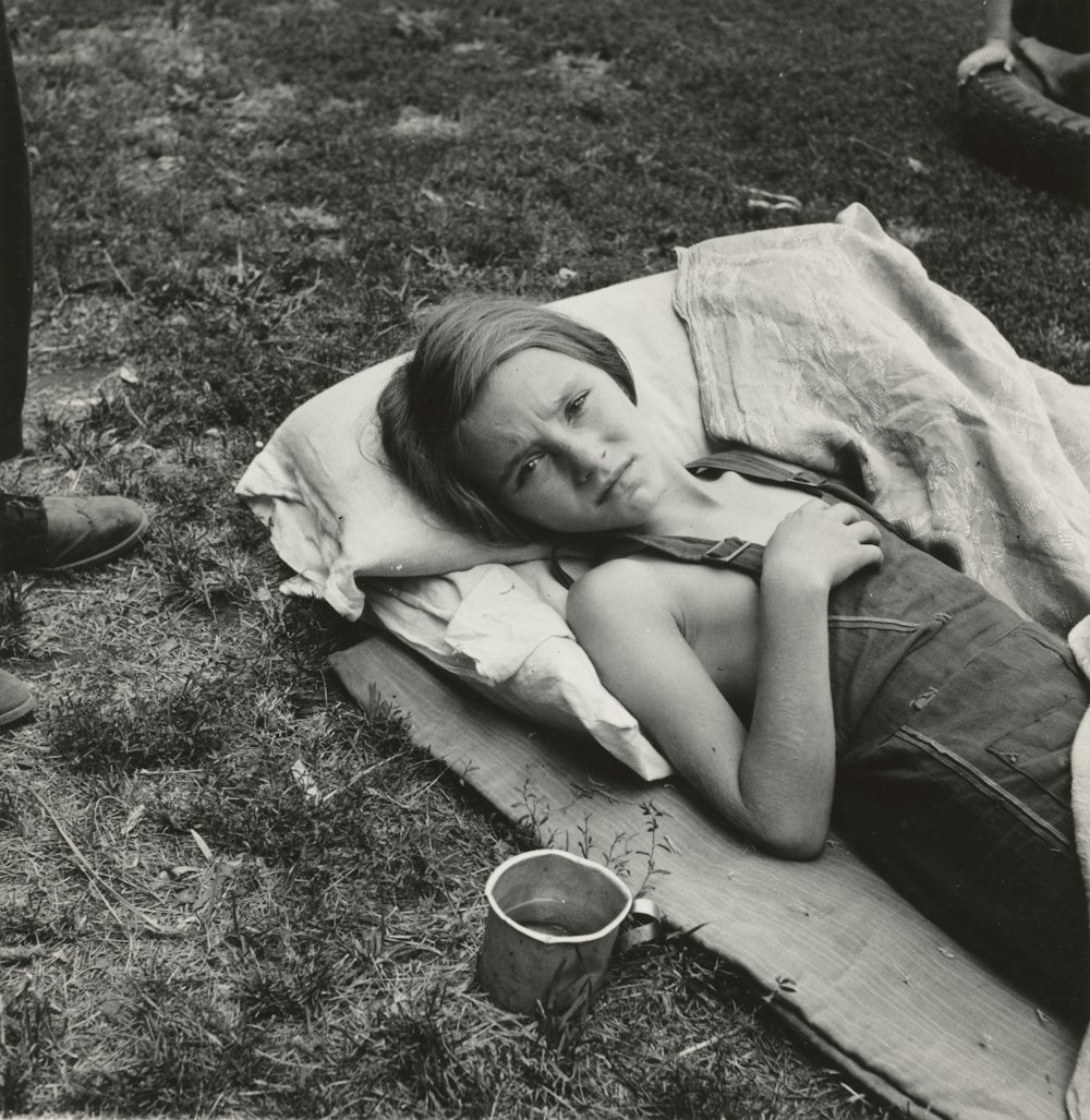 grayscale photography of girl lying near field