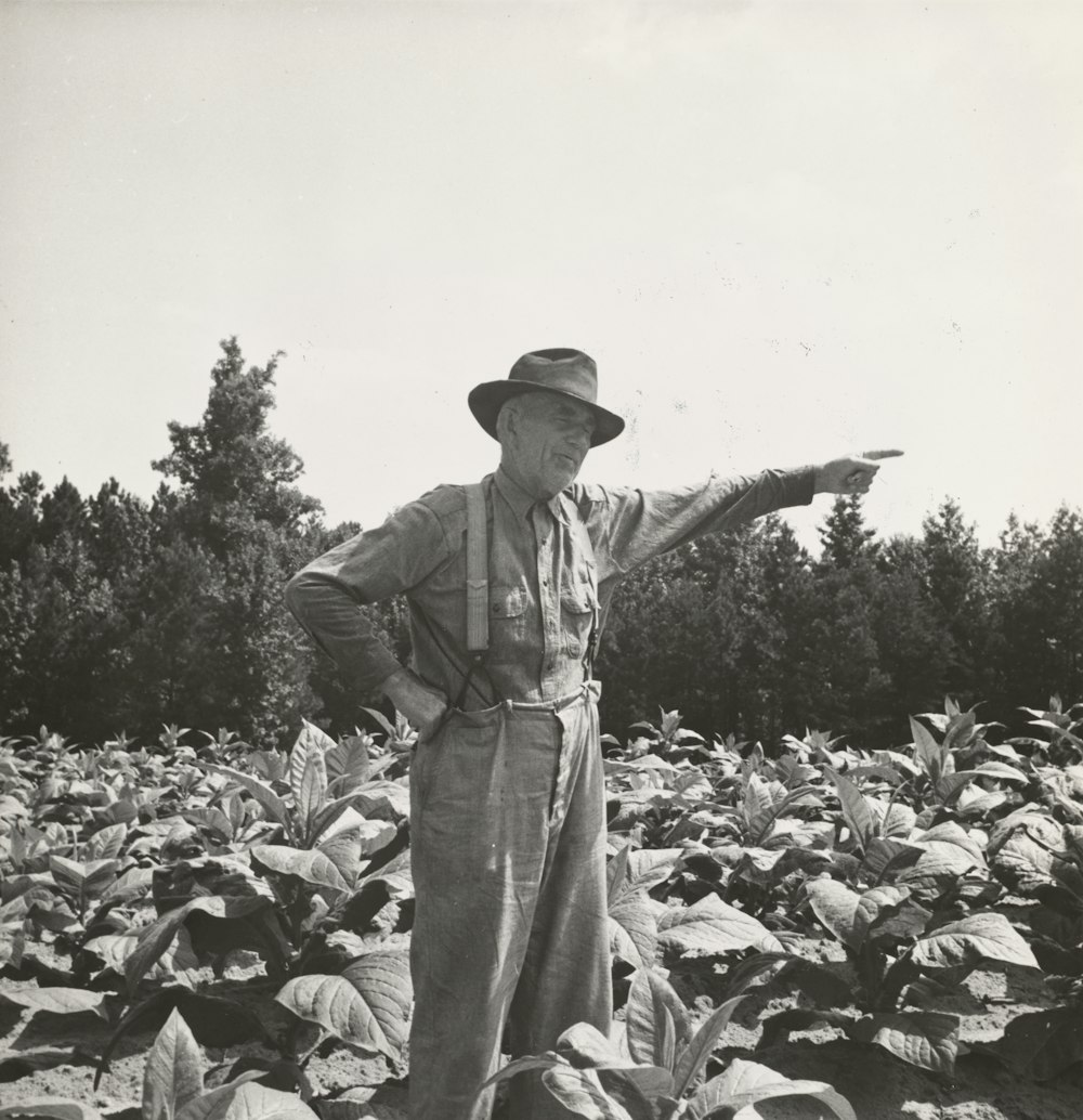 grayscale photography of old man standing on fiel