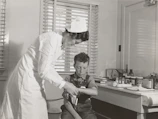A compassionate doctor gently examining a patient's arm cast in a bright hospital room