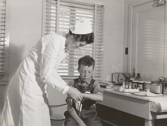 A physiotherapist gently assisting a patient with arm rehabilitation exercises in a bright treatment room.