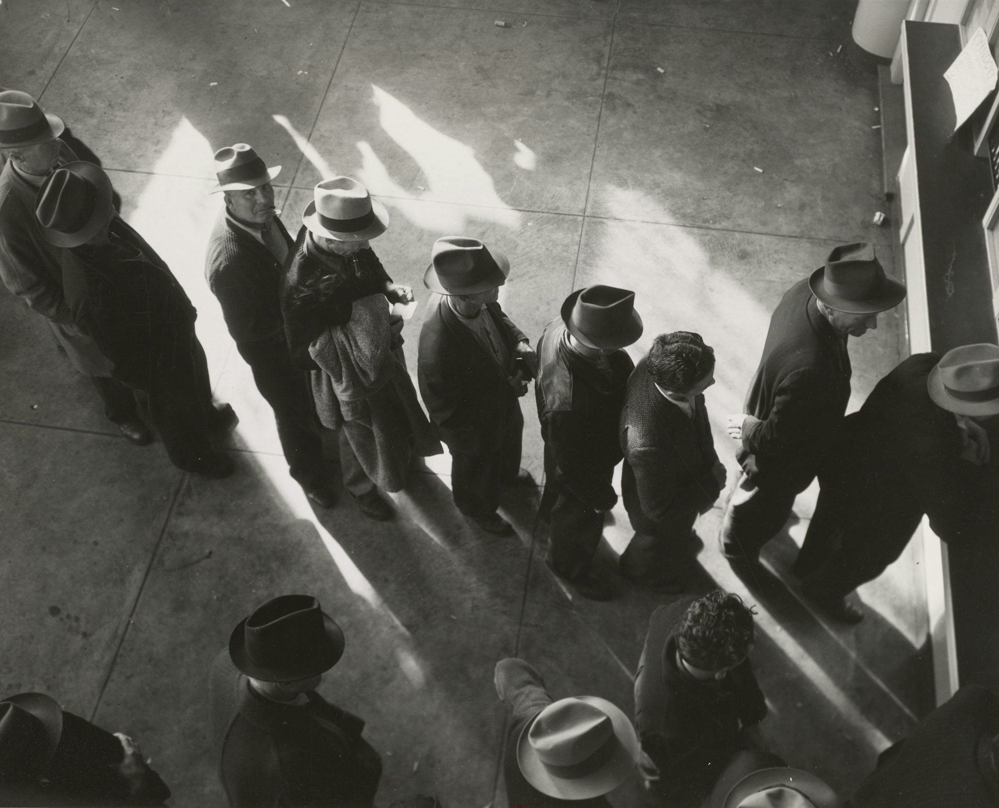 1938 - Unemployment benefits aid begins. Line of men inside a division office of the State Employment Service office at San Francisco, California, waiting to register for benefits on one of the first days the office was open.
Photographer - Dorothea Lange 