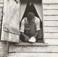 Craftsman carefully restoring a wooden window frame inside a Saint-Malo old town house.