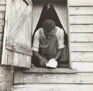Craftsman carefully restoring a wooden window frame inside a Saint-Malo old town house.