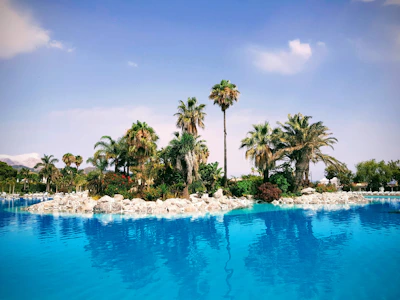 Close-up of sparkling clear pool water reflecting blue sky and palm trees.