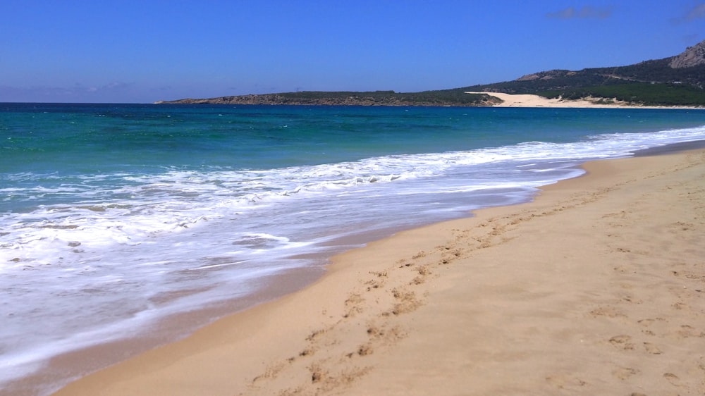 a sandy beach next to a body of water