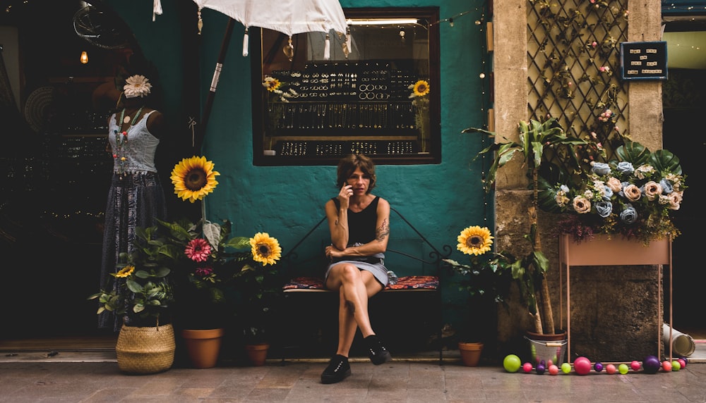 woman sitting on bench between sunflowers