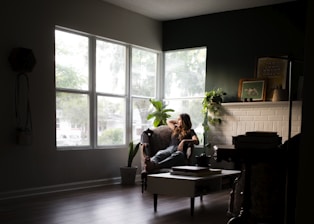 A woman cleaning a cozy living room with natural light coming through the window.