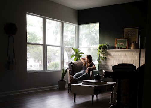 A woman happily cleaning a cozy living room with natural light.