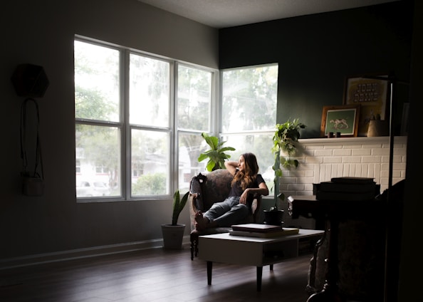 A friendly woman cleaning a cozy living room with natural light.