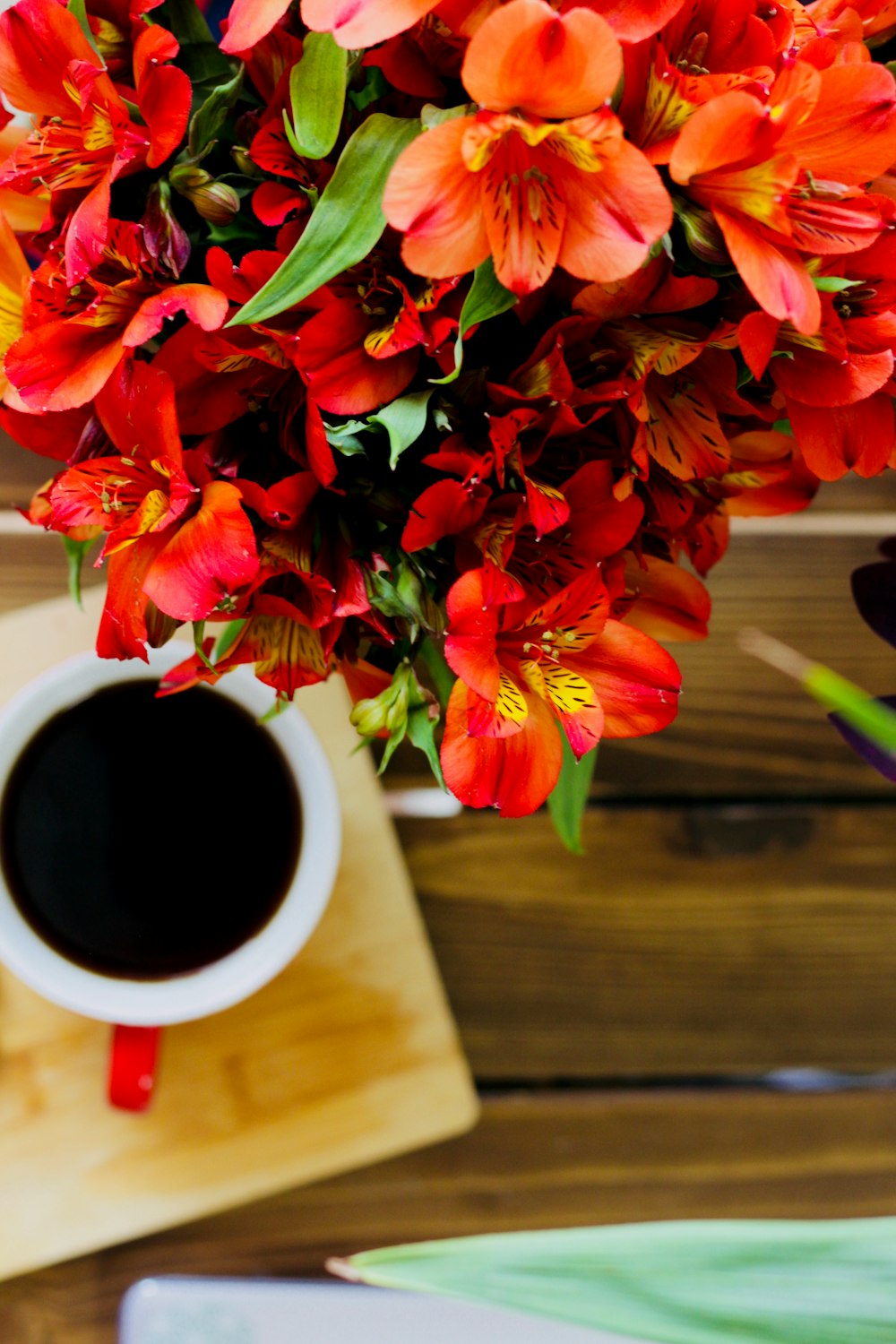 white ceramic mug with coffee near bouquet of flowers