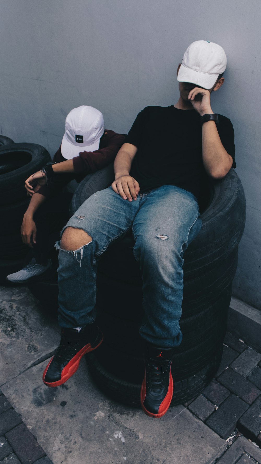 two people sitting on a tire talking on a cell phone