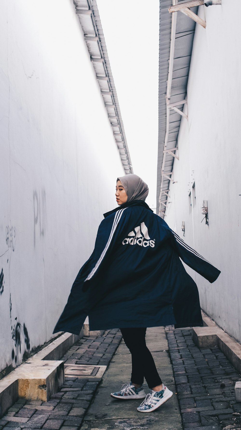 woman wearing blue adidas jacket on alley