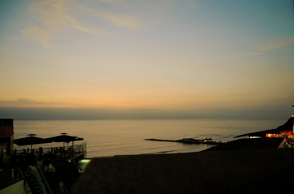 silhouette of parasol at the shore during sunset