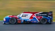 Close-up of a sleek race car featuring a bold red and black livery with detailed sponsor logos.