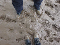 Close-up of firefighter's boots stepping through muddy terrain during a drill.