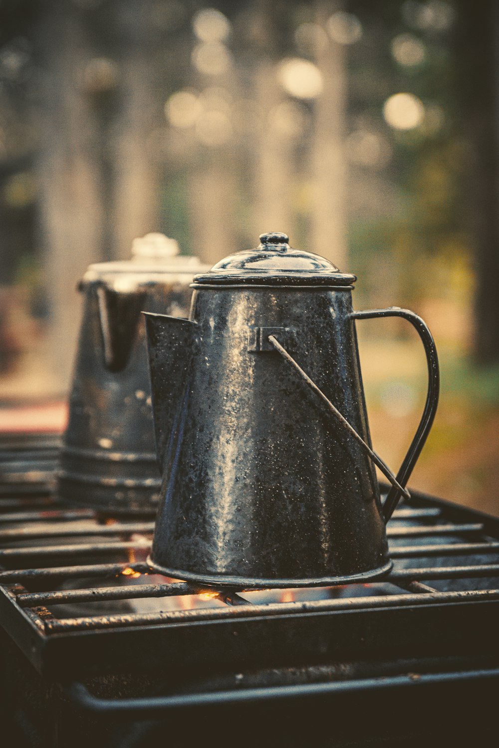 two grey metal kettles on black metal grill